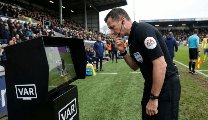 Главный арбитр матч смотрит повтор спорного эпизода с помощью системы VAR